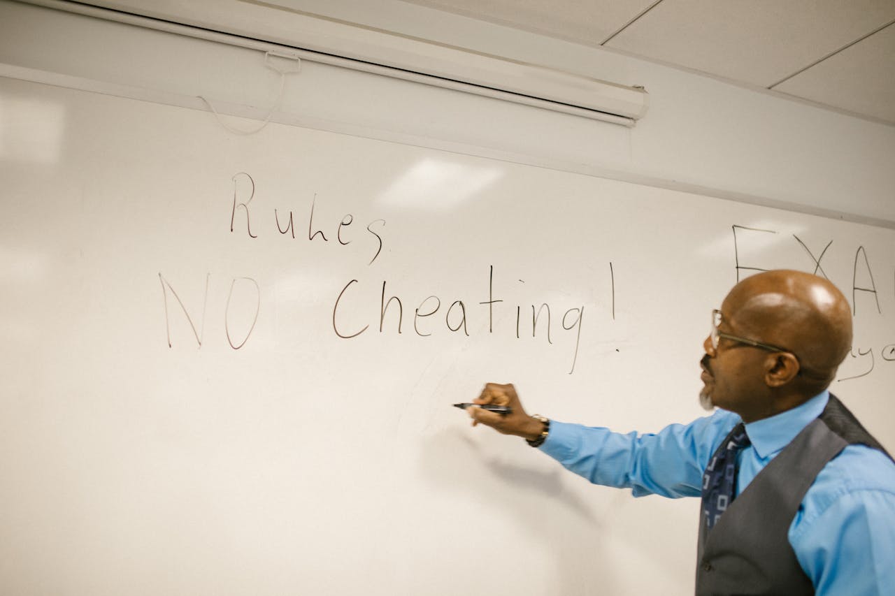 Teacher writes 'No Cheating!' on whiteboard during classroom instruction.
